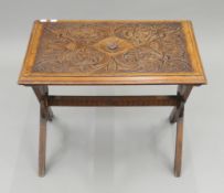 A Victorian carved walnut x-frame side table. 66 cm wide x 49.5 cm high.
