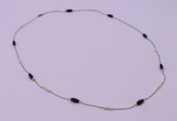 An 18 K white gold, onyx and seed pearl necklace. 65 cm long. 5.8 grammes total weight.