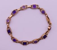 A 9 ct gold and amethyst line bracelet. 18 cm long. 12.9 grammes total weight.