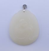 A silver-topped white jade pendant. 6 cm high including suspension loop.