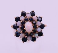 A 9 ct gold opal and sapphire cluster ring. Ring size P. 5.1 grammes total weight.