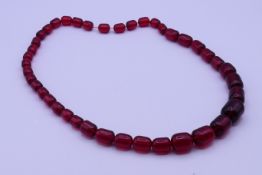 A cherry amber coloured bead necklace. 66 cm long.