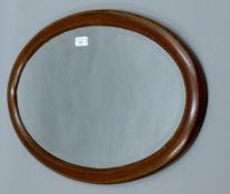 An Edwardian inlaid mahogany bevelled oval wall mirror. 64 cm wide.