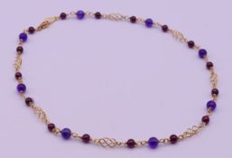 A gold, amethyst and garnet bead necklace. 40 cm long. 13.9 grammes total weight.