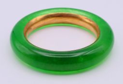 A gilt-lined jade bangle. 6 cm inner diameter.