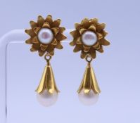 A pair of unmarked gold and pearl earrings, with associated backs.