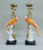 A pair of gilt metal-mounted porcelain parrot-form candle stands, each mounted on a plinth base.
