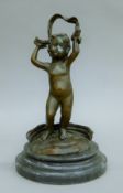 A bronze putto mounted on a marble plinth base. 28.5 cm high.