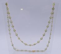 A gilt metal and green stone necklace. 80 cm long.