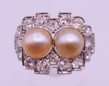 An unmarked high ct white gold or platinum diamond and pearl set ring. 1.5 cm high. Ring size S/T.
