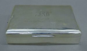 A silver cigarette box, the lid with presentation inscription. 12 cm wide.