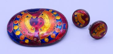 A silver and enamel brooch, and a pair of earrings. The former 5.3 cm wide.