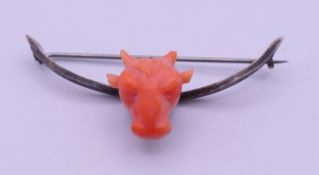 An unmarked silver and coral bull form brooch. 6 cm wide.
