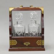 A brass-mounted mahogany two-bottle tantalus. 24.5 cm wide.
