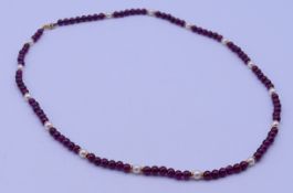 A 9 ct gold garnet and pearl necklace. 46 cm long.