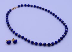 An 18 ct gold mounted lapis lazuli bead necklace and a matching pair of stud earrings.