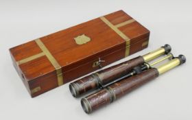 A large pair of crocodile skin-mounted binoculars housed in a brass-mounted mahogany case.