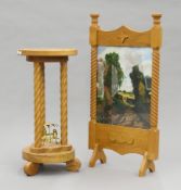 An oak side table and a fire screen centred with an oil painting of a country scene.