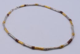 A tri-coloured silver necklace. 43 cm long.