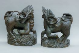 A pair of carved rosewood qilin. Each 35 cm high.