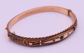 A boxed 9 ct gold sapphire set bracelet. 6 cm inner diameter. 8.4 grammes total weight.
