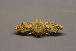 Hallmarked 15ct Yellow gold diamond bar brooch, with roped scrollwork decoration and a central