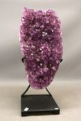 Large polished edge amethyst crystal geode on contemporary black metal stand, comprised of a large