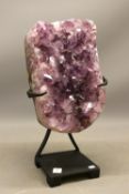 Amethyst geode with polished edge on contemporary black metal stand, comprised of one exposed