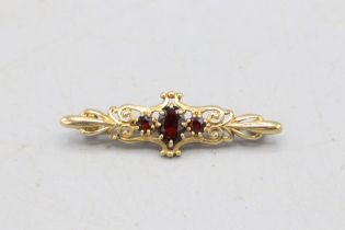 Hallmarked 9ct yellow gold garnet three-stone bar brooch, comprising one central oval-cut faceted