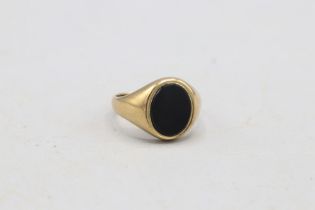 Hallmarked 9ct yellow gold onyx signet ring, comprising a 10 × 7.5mm oval onyx set within a plain