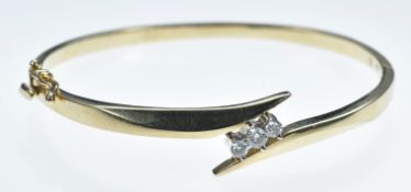 A 14k gold bangle set with three round cut diamonds of approximately 0.15ct, 0.1cr & 0.1ct, 14.9g