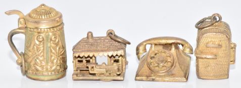 Four 9ct gold charms including a telephone, jug, train station with moving train and a fridge/