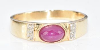 A 14k gold ring set with a ruby cabochon and two diamonds, 2.1g, size O