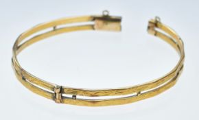 A yellow metal bangle with engraved decoration, tests as 21k gold (damaged clasp), 17.4g