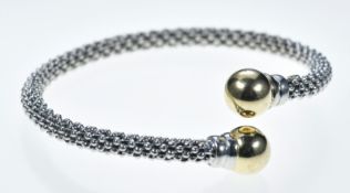 A 14k white gold torque bangle with yellow gold sphere finials, 13.8g