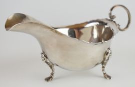 George V hallmarked silver sauce boat with wavy edge and scroll handle and raised on three lion mask