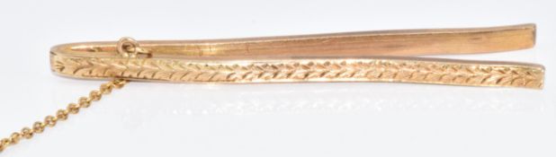 A yellow metal tie clip with engraved decoration, tests as 9k, 5.8g