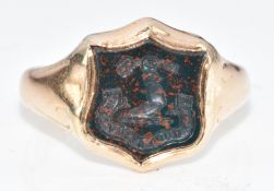 A c1900 yellow metal signet ring set with a bloodstone intaglio seal depicting a family crest