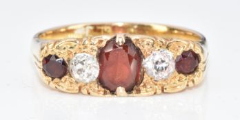 An 18ct gold ring set with an oval cut garnet, two old cut diamonds and two further round cut