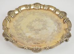 George V hallmarked silver salver with shaped edge and engraved decoration, raised on three ball and