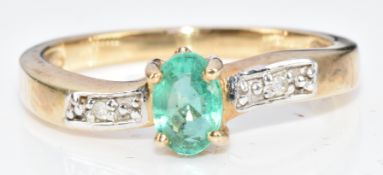 A 9ct gold ring set with an oval cut emerald and diamonds, 2.4g, size N