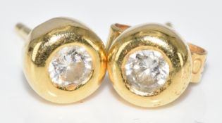 A pair of 18ct gold earrings each set with a round brilliant cut diamond of approximately 0.1ct, 1.