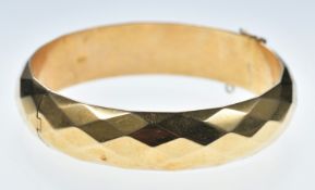 An 18k gold bangle with faceted decoration, 22.8g
