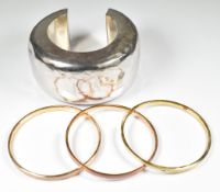 A silver bangle with hammered decoration and three silver gilt bangles set with enamel (104g)