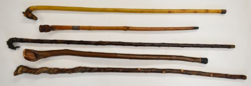 Five wooden walking sticks including one with brass handle in the form of a hound carrying a