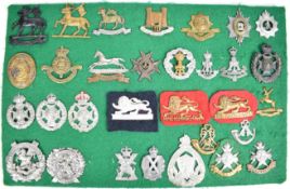 Thirty one cap badges and insignia including Cranleigh, Queen's, Suffolk Hussars, Worcestershire,