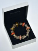 A silver Pandora bracelet with twelve 14k gold charms, six silver and glass charms and 14k gold