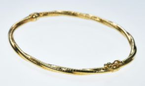 A 9ct gold bangle with a twist design and ridged decoration, 4.4g