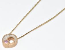 A 9ct gold 'Celtic Shell' pendant set with three diamonds and a pink sapphire, on 9ct gold chain, in