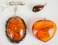 A large pressed amber heart shaped pendant with 14k gold pendant loop, large silver brooch set